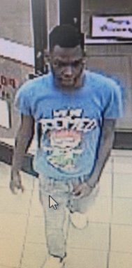 Suspect standing in store with a blue shirt on