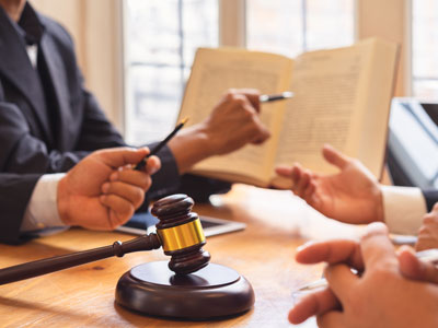 People pointing and discussing a book with a gavel on the table
