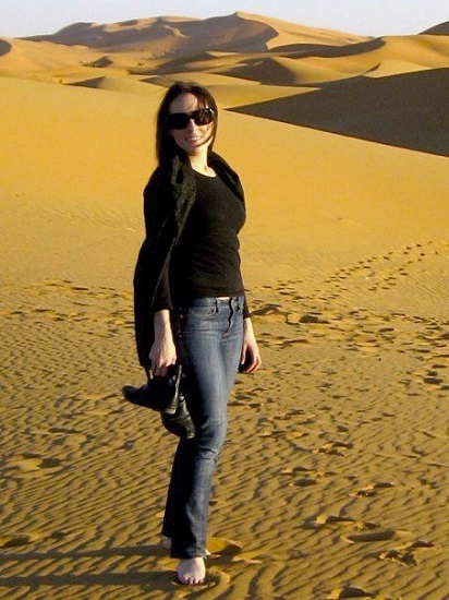Cara stands in front of sand dunes.