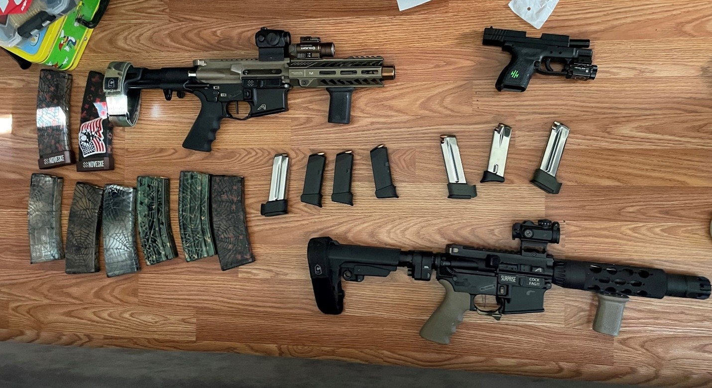 On a table, AR-type pistols, one 9 mm pistol, one suppressor, two body armor plates