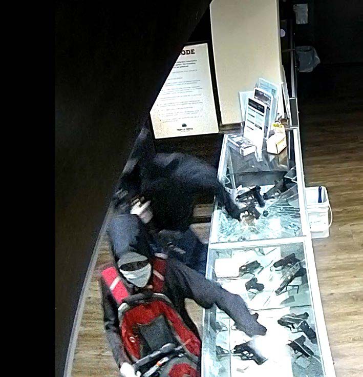 Two suspects breaking glass displays with firearms in them