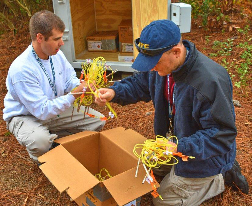 Two industry operations investigators practice inspecting inventory during IOI basic training