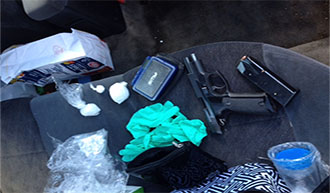 Image of a automobiles interior littered with a pistol, drugs and ammo