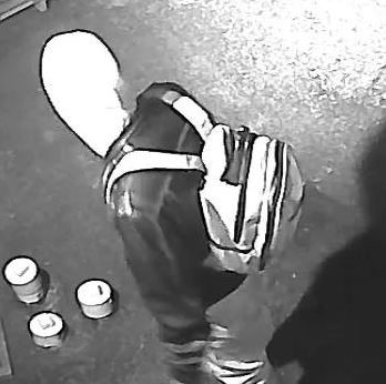 Image of suspect 1 with a black jacket and a hood on, wearing a light bookbag.