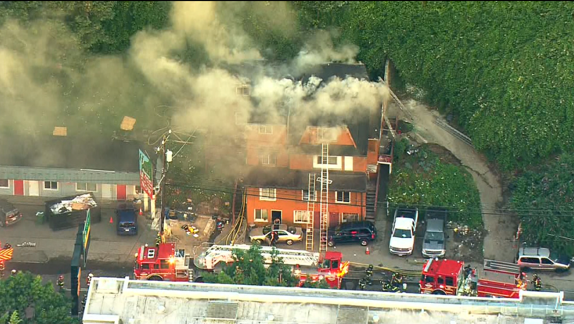 An aerial view of a building surrounded by firetrucks and smoke