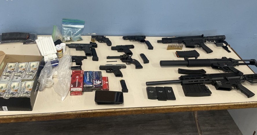Firearms seized as a result of Operation Show Me Justice Firearms, currency, and other items laying on a table.