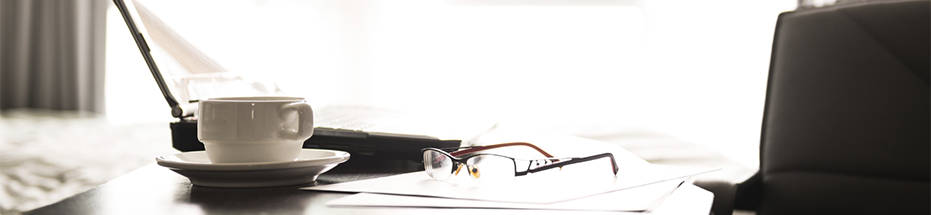 Image of a laptop, newspaper and a pair of glasses
