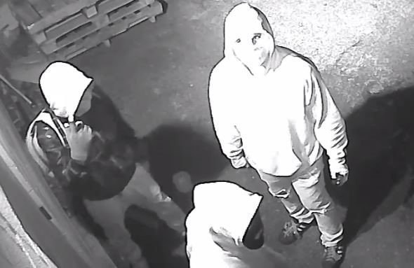 Image of 3 suspects; one with a black jacket and a hood on, wearing a light bookbag; two wearing light hoodies with face masks on.