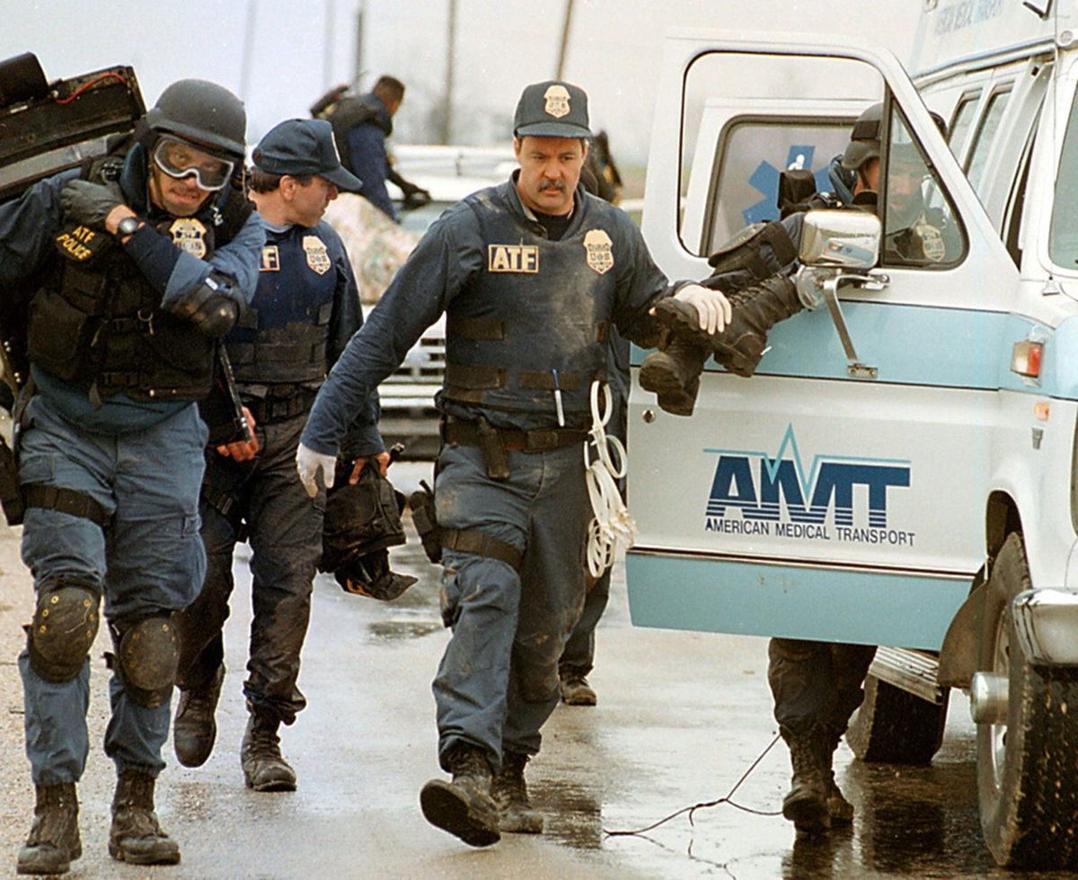 ATF agents help a wounded agent in a local ambulance.