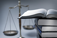 Imagen de una pila de libros de leyes con la balanza de la justicia