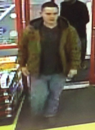 Image of suspect wearing a green military styled jacket, black t-shirt, blue jeans and black shoes.