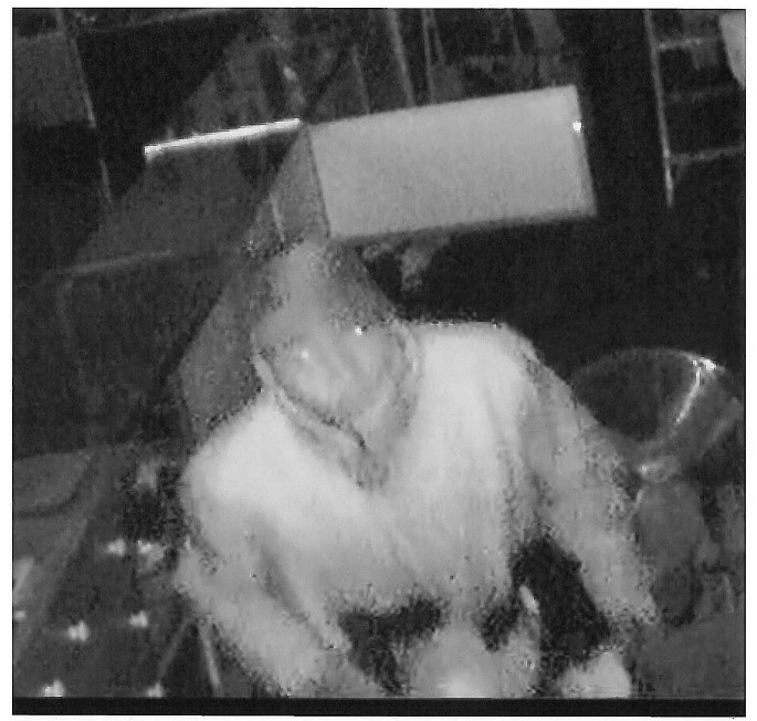 Image of a suspect wearing a dark hat and light clothing.