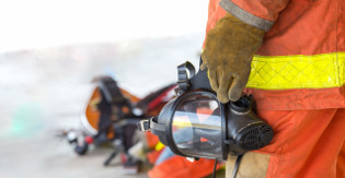 Un bombero de uniforme sosteniendo una máscara de gas