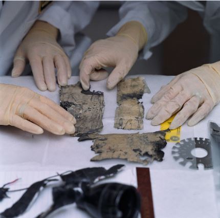A forensic specialist examines fragments of an exploded pipe bomb