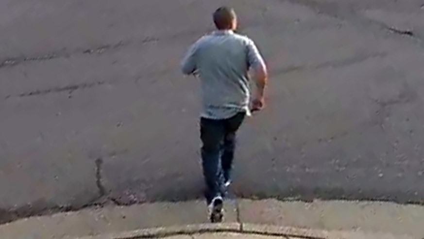 Back view of male suspect in gray polo shirt, dark pants and white shoes