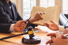 People pointing and discussing a book with a gavel on the table