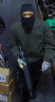 A person in dark-colored clothes with their face covered at the scene of the crime.