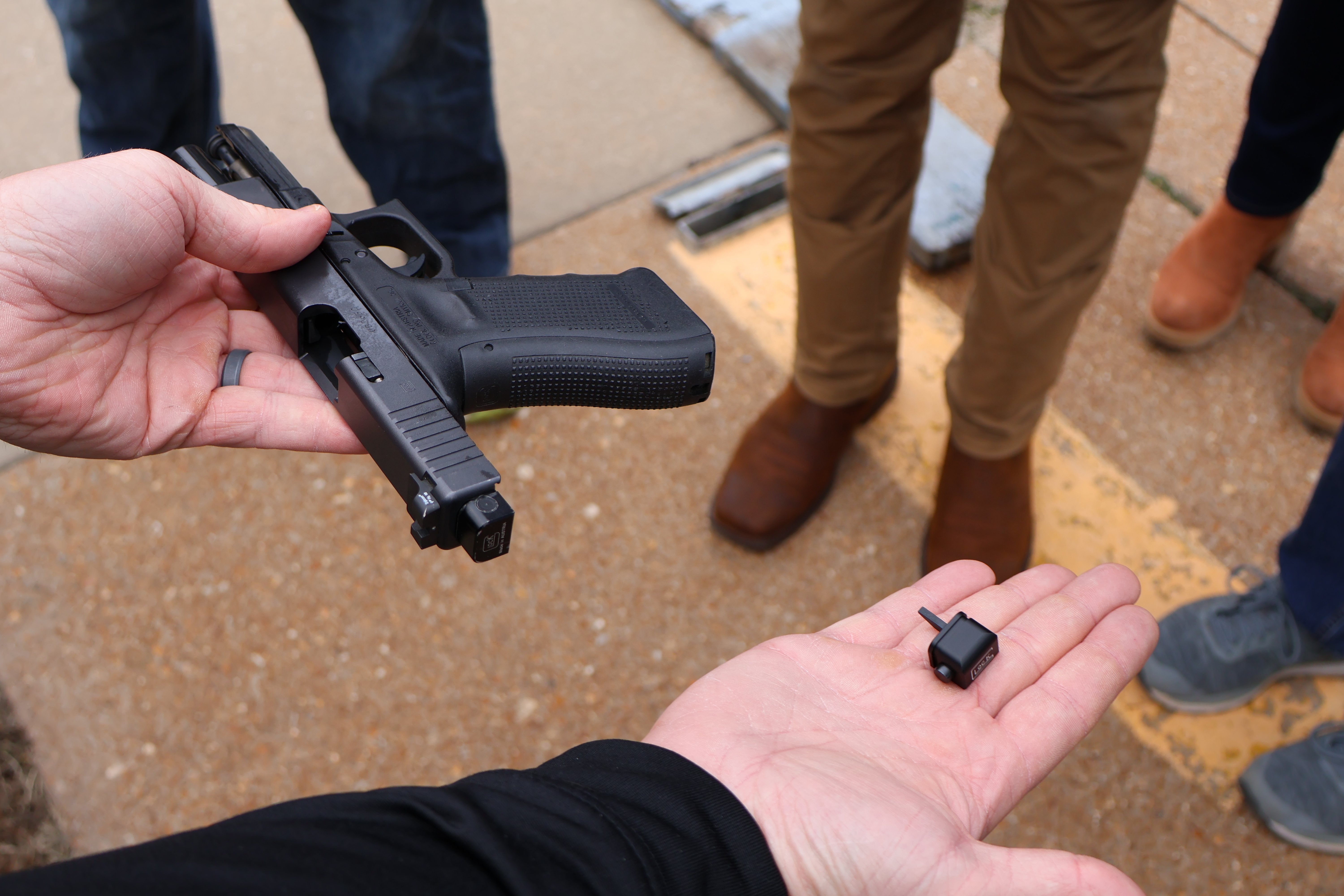 A person holding a firearm in one hand and a conversion device in their other hand.