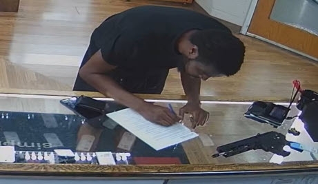 A person in a dark-colored shirt signing a form.