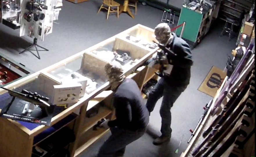 Two suspects in full face masks burglarizing a gun shop.
