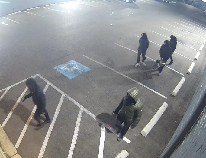 Five people in dark-colored clothing in a parking lot.