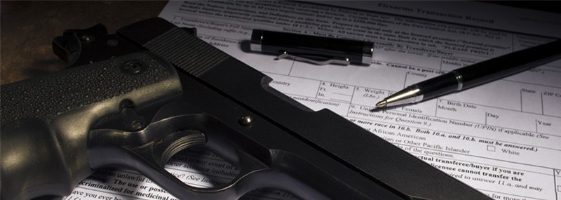 Firearm and pen placed on top of firearms transaction record form
