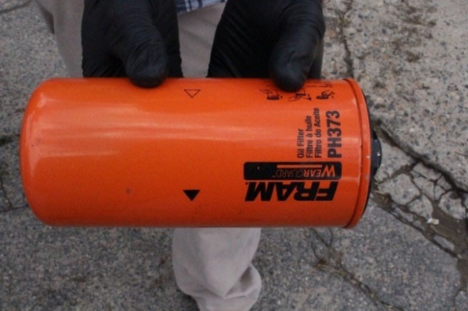 A Fram oil filter held by a person wearing gloves