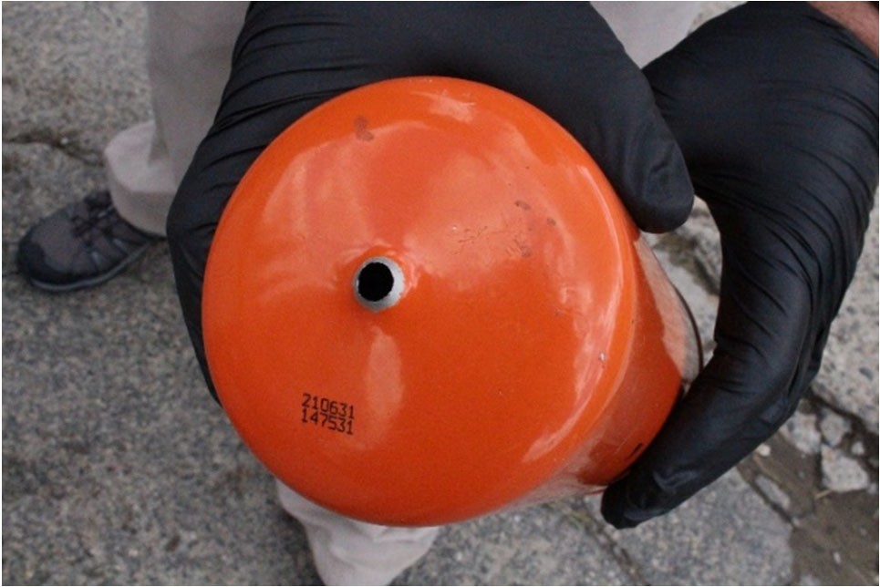 The top of a Fram oil filter displayed by a person wearing gloves