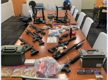 Table with guns 3D printers and bullets that were seized