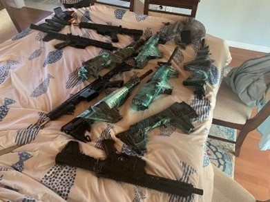 Multiple guns laying on a bed