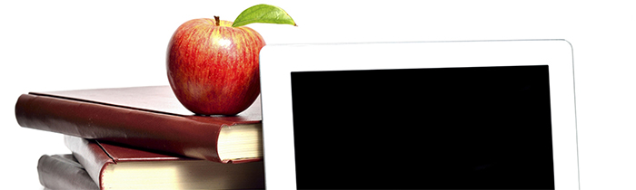 Image of an apple atop a text book, next to an e tablet