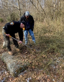 Two ATF Certified Fire Investigators searching a wooded area for evidence.
