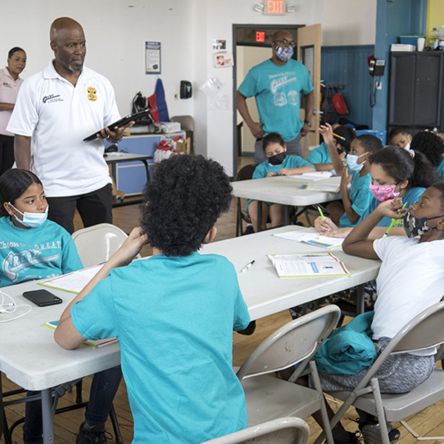 G.R.E.A.T instructor talking to group of kids sitting at a table