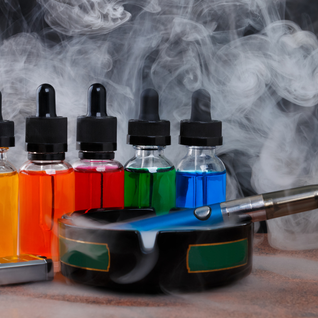 Flavored liquid next to a vape in an ashtray