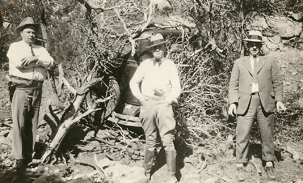 Searchers posing in front of Sutton's partially visible sedan