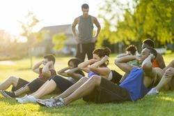 A group of people doing sit ups outdoors