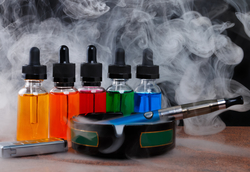 Flavored liquid next to a vape in an ashtray