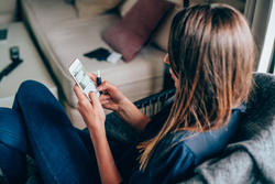 A woman holding a cellphone and e-cigarette in her hand