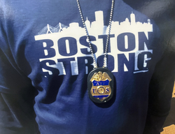 Agent wearing a blue shirt which reads Boston Strong with a badge on his chest