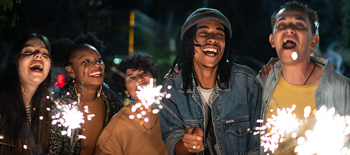 Group of people holding fireworks and smiling