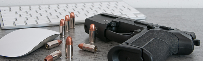 Gun and bullets next to a computer keyboard