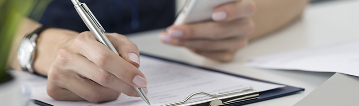 A person using a smartphone to assist in filling out a form