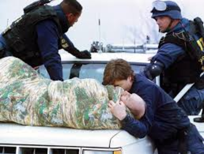 A wounded ATF special agent being transported on the hood of a pick-up truck to receive medical attention.