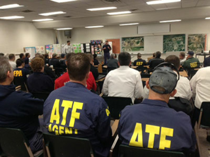 Group of agents sitting in a classroom listening to a briefing