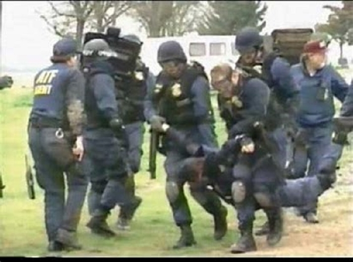Four ATF agents move an injured agent to receive medical attention. 