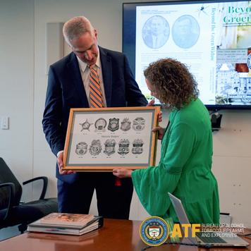 ATF Assistant Director Brent Beavers presents a plaque of historic badges to Juanita Green Hollinghead